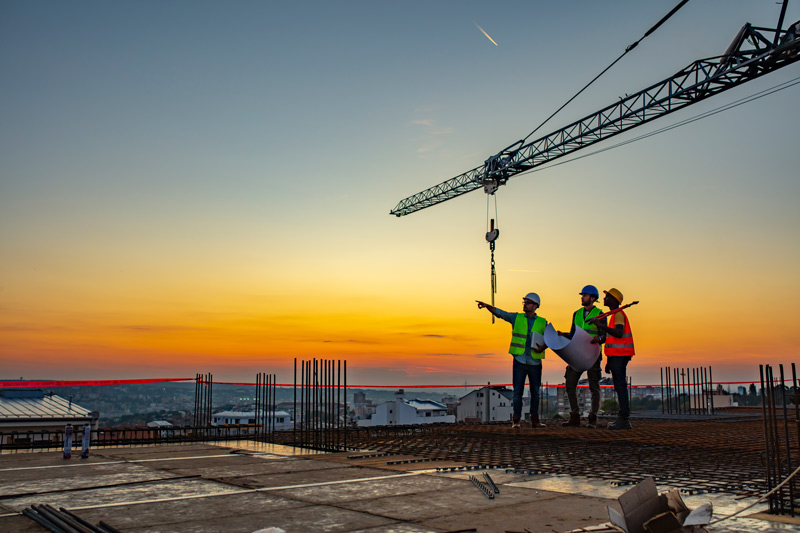 Multi ethic workers talking at construction site reviewing plans